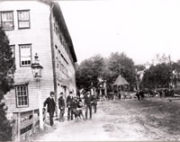 Fountain Place c. 1900                                                                                                                                                                        No respectable man would be seen out with his derby at the time of this photo. The scene is what is now known as P.T. Barnum Square.   The large wood-frame building that occupied the site at this time was the Cole-Ambler hat factory (later known as the Higson hat factory, and later yet the Fay-Gorman hat factory). The structure burned to the ground on August 26, 1913, producing one of Bethel’s most spectacular fires. The factory’s smokestack, however, survived until 1934. The bandstand in the background occupied the island that is now home to the Libby Kellogg Memorial. 